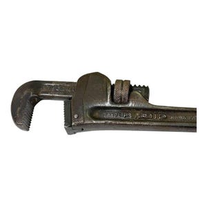 May include: A vintage, rusty, gray metal pipe wrench with the text "TRADE MARK PAT" and "RIDID" on the handle.