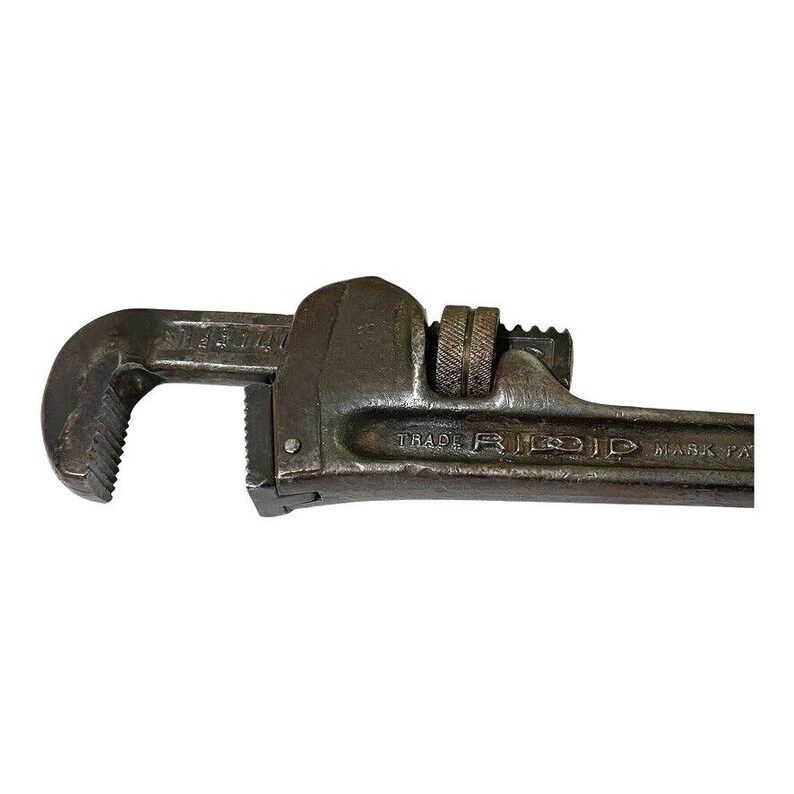 May include: A vintage, rusty, gray metal pipe wrench with the text "TRADE MARK PAT" and "RIDID" on the handle.
