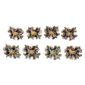 May include: Eight ceramic flower-shaped dishes with a yellow center and purple, green, and white swirling designs.