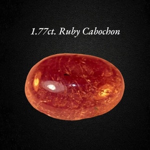Può includere: Un cabochon di rubino da 1,77 carati. Il rubino è di colore rosso intenso con una superficie liscia e lucida.