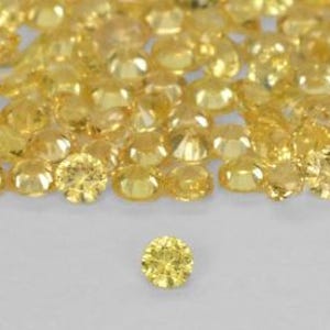 Może przedstawiać: Duża grupa małych, okrągłych, żółtych kamieni szlachetnych, z jednym większym kamieniem szlachetnym na pierwszym planie. Kamienie szlachetne są fasetowane i mają błyszczące, błyszczące wykończenie.