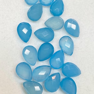 May include: A collection of 17 light blue gemstone teardrop beads. The beads are faceted and have a smooth, polished finish.