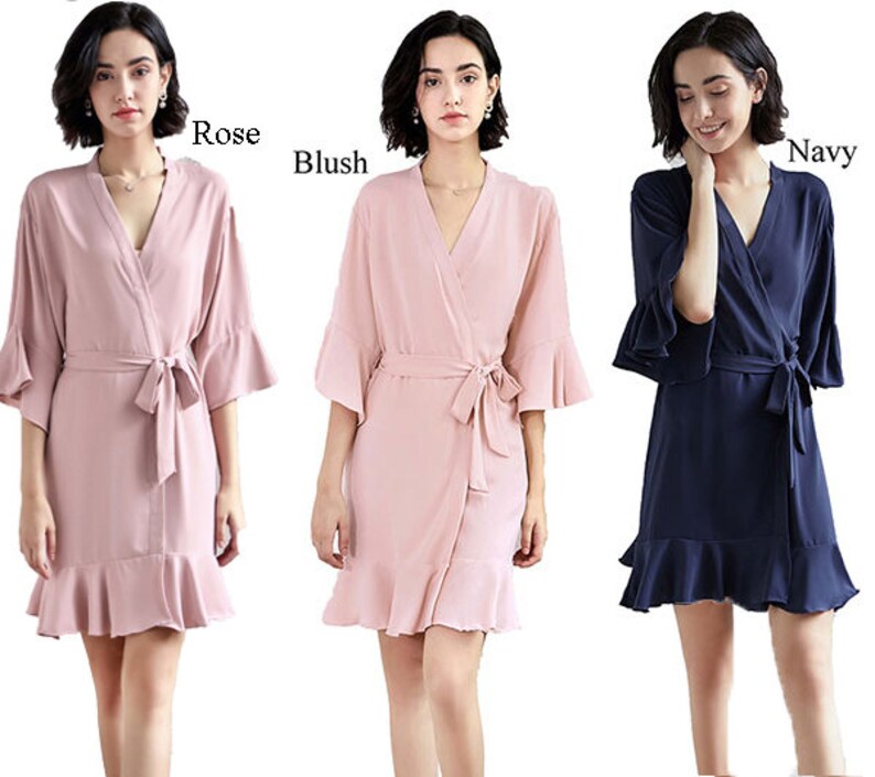 May include: Three women's robes in pink, blush, and navy blue with ruffled trim and a tie belt. The robes are made of a soft, silky fabric and are perfect for getting ready for a special occasion.