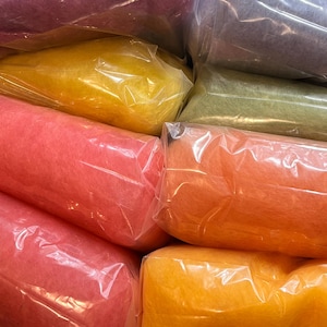 May include: A collection of wool roving bundles in various colors including magenta, yellow, olive green, pink, orange, and gold, each individually packaged in clear plastic bags and arranged together in a group for storage and organization.