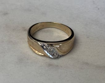May include: A gold and silver band ring with a row of small diamonds set in the silver band.