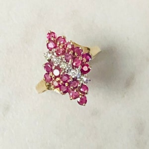 May include: A gold ring with a cluster of pink rubies and white diamonds. The ring is set in a delicate, vine-like design.