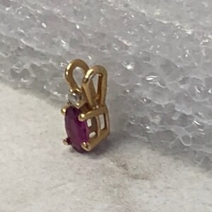 May include: A gold pendant featuring a ruby gemstone and a small diamond accent.