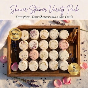 May include: A wooden tray holds a variety pack of shower steamers. The steamers are round and white, some with floral accents. The text reads "Shower Steamer Variety Pack" and "Transform Your Shower into a Spa Oasis". The image also includes a bottle of oil and the text "Handmade 100% Organic".