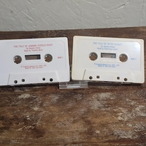 May include: Two vintage audio cassette tapes. One tape is labeled "The Tale of Jemima Puddle-Duck" by Beatrix Potter, read by Timothy West. The other tape is labeled "The Tale of Peter Rabbit" by Beatrix Potter, read by Rosemary Leach.