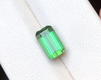 May include: A green gemstone with a rectangular shape and a faceted cut.
