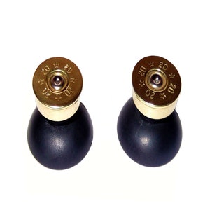 May include: A pair of distinctive earrings. Each earring has a gold-coloured top with the number "20" and a star design, atop a black, rounded base. The earrings are set against a white background.