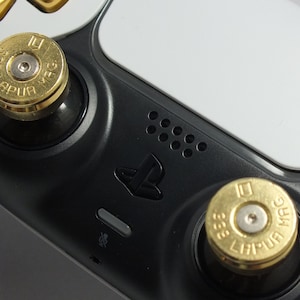 May include: A close-up of a white and black video game controller with two gold bullet-shaped buttons. The buttons have the text "38 SPECIAL" and "LAPUA MAG" on them.