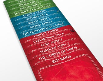 May include: A set of ten unique cards for a card game. The cards are red, blue and green with gold lettering. The cards are labelled with the names of the decks and aspects, such as "Charm Deck", "Thorn Aspect", "Bloom Aspect", "The Blight of Nevers", "Natural Deck", "Might Aspect", "Storm Aspect", "The Frostwild Scourge", "Ceremonial Deck", "Fury Aspect", "Shadow Aspect", "The Corpse of Viros", and "Red Rains".