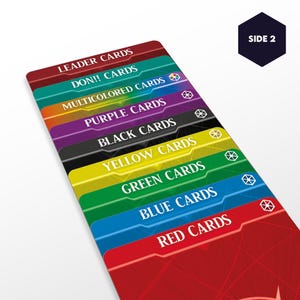 May include: A set of playing cards with different colored backs. The cards are arranged in a stack, with the red cards on the bottom and the leader cards on the top. The text on the cards reads "Leader Cards", "Don!! Cards", "Multicolored Cards", "Purple Cards", "Black Cards", "Yellow Cards", "Green Cards", "Blue Cards", and "Red Cards".