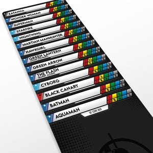 May include: A black game mat featuring a list of DC characters including Zatanna, Wonder Woman, Superman, Starfire, Nightwing, Martian Manhunter, Hawkgirl, Green Lantern, Green Arrow, The Flash, Cyborg, Black Canary, Batman, and Aquaman with DC Core Box text.