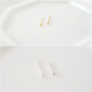 May include: Two pairs of nose rings, one pair is gold and the other is silver. The nose rings are simple and have a small round stud.