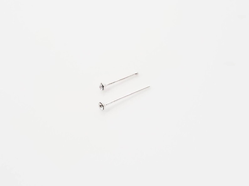 May include: Two silver earring posts with small, round, silver tops.