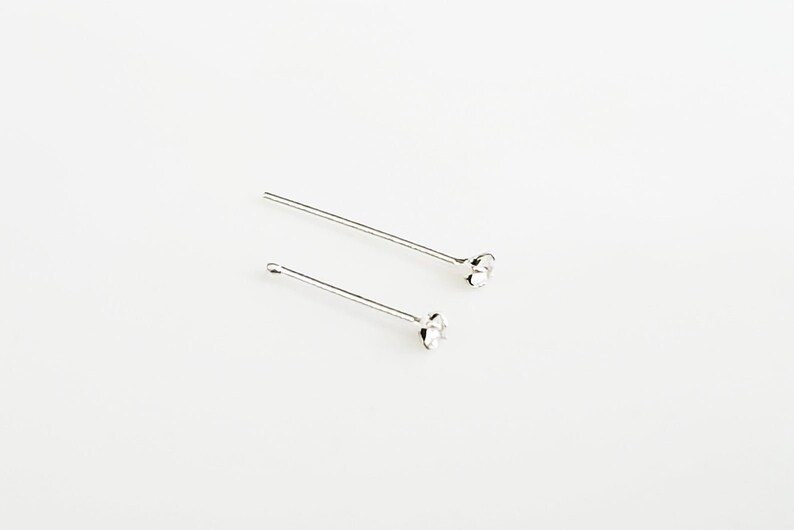 May include: Two silver nose studs with small round clear stones at the ends.