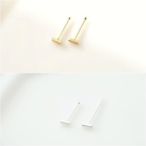 May include: Two pairs of minimalist earrings, one pair in gold and one pair in silver. Each earring features a small, rectangular bar.