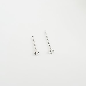 May include: Two silver nose rings with clear rhinestones. The rings are straight and have a simple design.