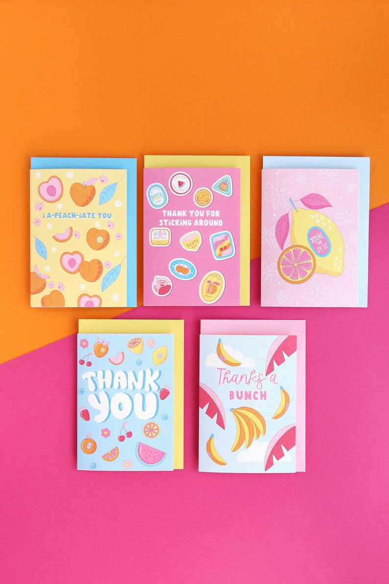 Pu&ograve; includere: Cinque biglietti d'auguri con un tema di frutta. I biglietti sono rosa, gialli e blu con vari frutti come limoni, pesche, banane, angurie e ciliegie. I biglietti hanno messaggi diversi, tra cui "I-a-peach-iate you", "Thank you for sticking around", "Thank you", "Thanks a bunch", e "You're the zest".
