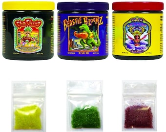 May include: Three plastic containers of plant fertilizer with labels that read "Cha Ching 0-50-10", "Beastie Bloomz 0-50-30", and "Open Sesame". Each container is next to a small plastic bag containing the fertilizer in a different color: yellow, green, and purple.