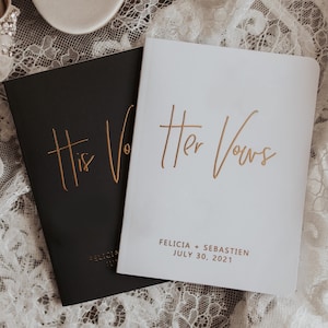 May include: Two white satin bridal shoes with jeweled embellishments and two small black and white books with gold lettering that reads "His Vows" and "Her Vows". The books also include the names "Felicia + Sebastien" and the date "July 30, 2021".