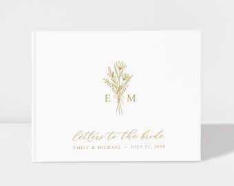 May include: White book with gold foil text that reads "letters to the bride." The book features a floral design with the initials "E M" in the centre.