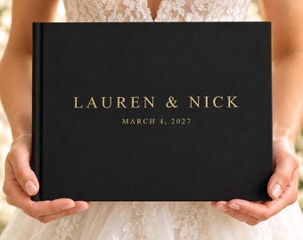 May include: A black rectangular photo album with gold foil lettering that reads LAUREN & NICK and MARCH 4, 2027. The cover has a smooth, matte texture and a clean, centered layout for the names and date in a classic serif font.