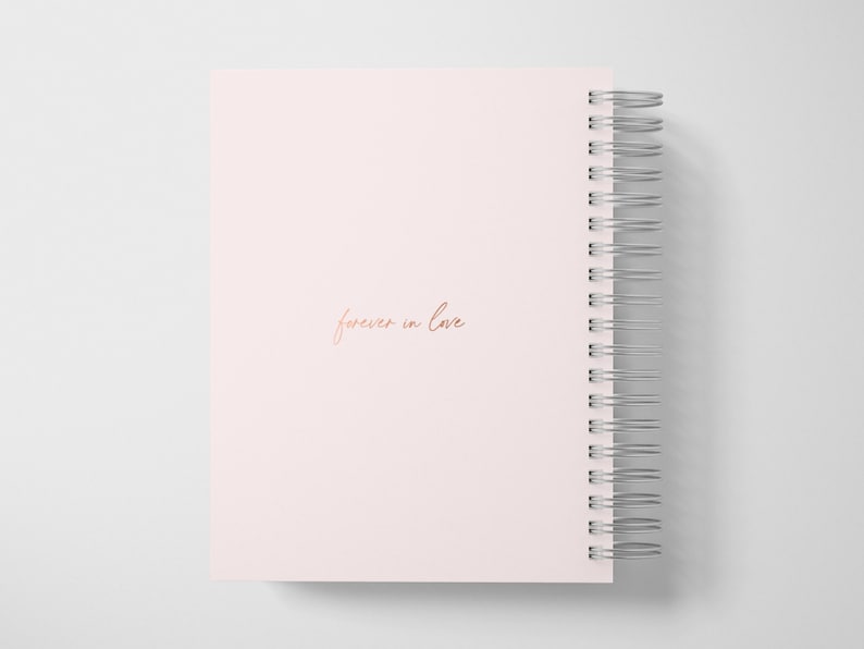 May include: A pink spiral bound notebook with the words "forever in love" written in rose gold lettering.