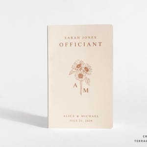 Könnte beinhalten: Ein cremefarbenes Heft mit terrakottafarbenem Text und einer Sonnenblumenillustration. Das Cover zeigt den Text SARAH JONES, OFFICIANT, ALICE & MICHAEL, JULY 21, 2029 sowie die Buchstaben A und M neben der floralen Grafik.