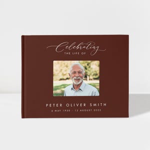 May include: A burgundy photo album with the words "Celebrating the Life of" in elegant script. A framed photo of a smiling man is centered on the cover, with the name "PETER OLIVER SMITH" and dates below.