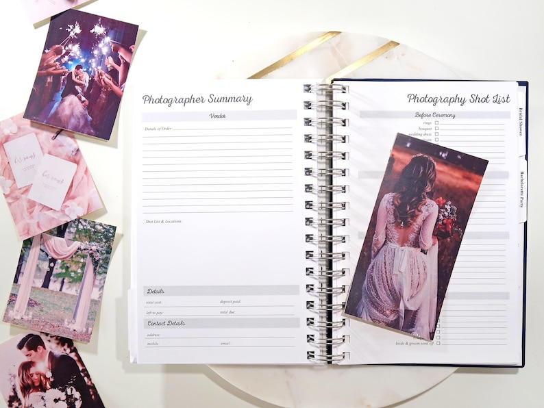 May include: A white spiral bound notebook with a blue cover and gold accents. The notebook has a section labeled "Photographer Summary" and another section labeled "Photography Shot List".