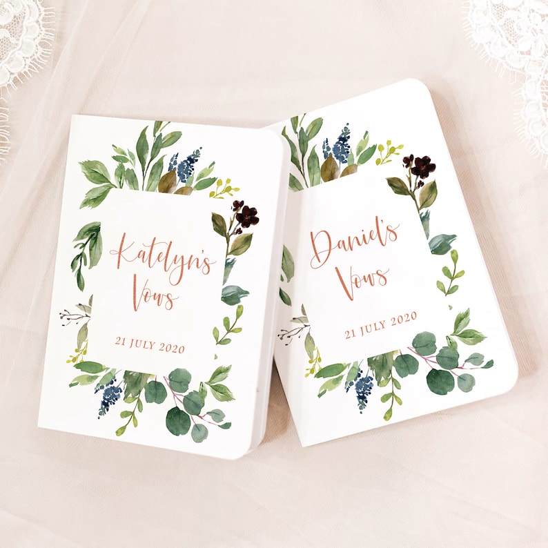 May include: Two white vow books with a watercolor floral design. The books are titled "Katelyn's Vows" and "Daniel's Vows" with the date "21 July 2020" printed below.