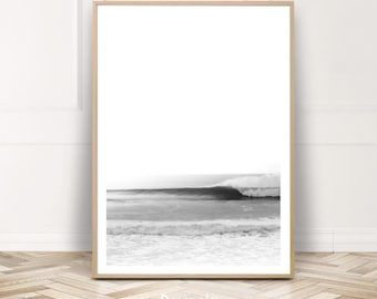 Può includere: Stampa incorniciata in bianco e nero di un'onda che si infrange nell'oceano. L'opera d'arte presenta uno stile minimalista che mette in risalto la bellezza naturale del mare. La cornice è in legno chiaro. Il testo "Paula's Gallery" è in basso.
