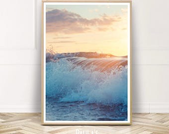 May include: A photograph of a wave crashing in the ocean at sunset. The water is a vibrant blue and the sky is a soft orange and pink.