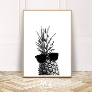 May include: A black and white photograph of a pineapple wearing sunglasses. The pineapple is in focus and the background is blurred.