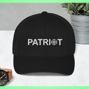Puede incluir: Gorra de béisbol bordada en blanco y negro con la palabra "PATRIOT" y un símbolo de diana.