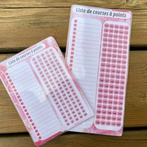 Op de afbeelding: Twee roze en witte boodschappenlijstjes met een marmerpatroon en gouden accenten. De lijstjes zijn getiteld "Liste de courses à points" en hebben genummerde regels om items op te schrijven. Het grotere lijstje heeft nummers van 101 tot 200, terwijl het kleinere lijstje nummers van 1 tot 100 heeft.