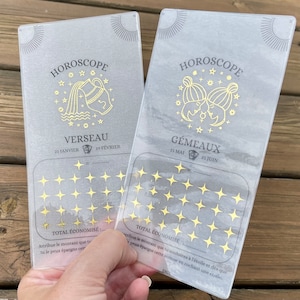 Peut inclure: Deux cartes en plastique transparent avec des accents en feuille d'or. Chaque carte présente un signe du zodiaque, le nom du signe et les dates du signe. La carte de gauche est pour le signe Verseau, et la carte de droite est pour le signe Gémeaux. Chaque carte a une grille d'étoiles pour le suivi.