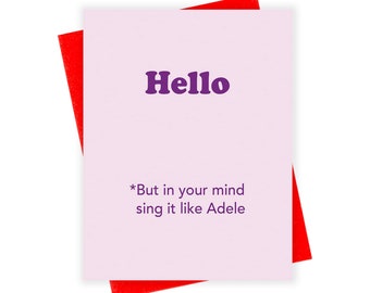 May include: A pink card with a red envelope. The card has the word "Hello" in purple text and the text "*But in your mind sing it like Adele" in black text.