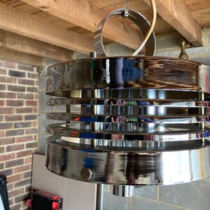 May include: A chrome ceiling light fitting with a circular design and multiple layers. The light fitting has a modern, mid-century style.