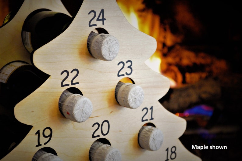 May include: Wooden Christmas tree wine rack with 24 numbered slots for wine bottles. The rack is made of light wood and has a natural finish. The numbers are black and are printed on the front of the rack. The rack is shown in front of a fireplace.
