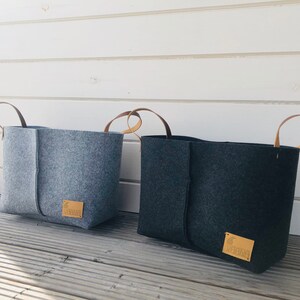 May include: Two felt storage bins with leather handles. The bin on the left is light gray and the bin on the right is dark gray. Both bins have a small brown leather tag with the word "GREEN" printed on them.