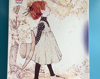 May include: A vintage jigsaw puzzle box featuring a girl in a polka dot dress looking up at a bird in a nest. The box is white with blue text that reads "Casse-Tête MB Puzzle Morceaux 500 Pieces".