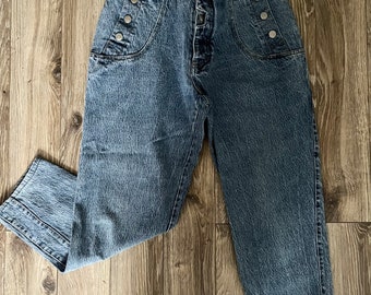 May include: A pair of light blue denim jeans with a high waist and button fly. The jeans have a relaxed fit and feature decorative buttons on the front pockets.