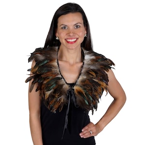 Puede incluir: Un chal de plumas marrón, negro y verde con un lazo de cinta de satén negro. El chal lo lleva una persona con el pelo largo y oscuro.