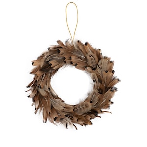 May include: A decorative wreath made of brown feathers with black tips, suspended by a gold string. The wreath is circular, with a white center, and is suitable for seasonal or year-round home decor.