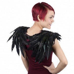 Puede incluir: Accesorio de disfraz de alas de plumas negras. Las alas est&aacute;n hechas de plumas negras y est&aacute;n unidas a una base de tela negra.