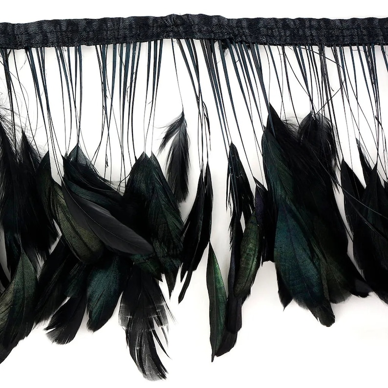 May include: Black feather fringe trim with a woven top edge. The feathers have a slight iridescent sheen, adding depth to the solid black color. The fringe is densely packed with feathers of varying lengths, creating a textured look.